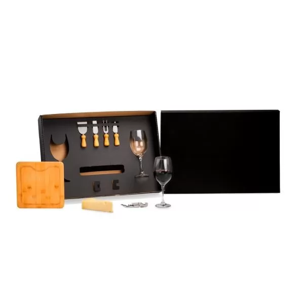 Kit para queijo e vinho preto aberto com taças de vidro, tábua de bambu e talheres sobre fundo branco