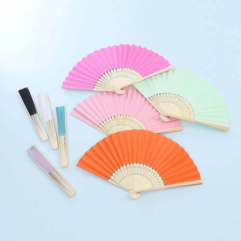 Leques de bambu abertos e fechados em cores variadas como laranja, pink e verde claro sobre fundo azul